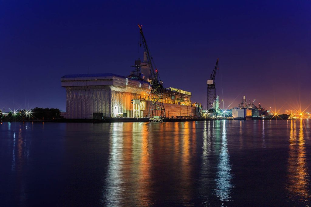 Shipyard repair at night with light reflections in bay