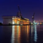Shipyard repair at night with light reflections in bay