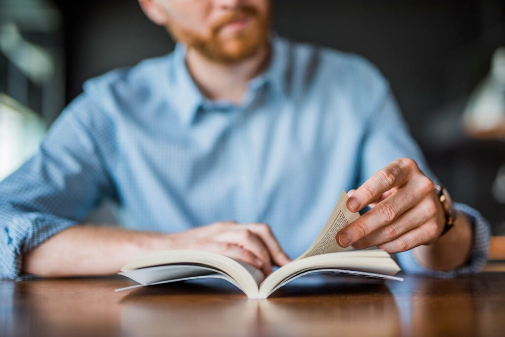Young man reading a book hand close up.